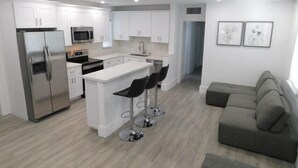 A modern kitchen with white cabinets, stainless steel appliances, and a central island with bar stools.