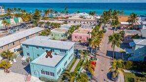 A coastal town with a prominent turquoise building, palm trees, and a view of the ocean.