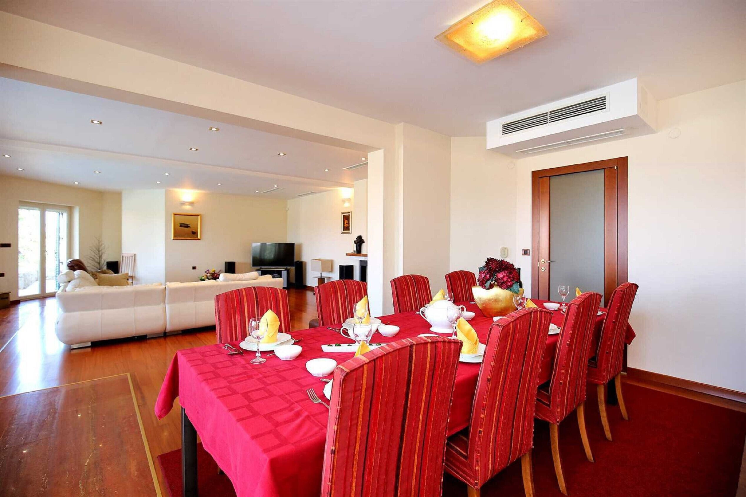Un coin repas avec une nappe rouge, des chaises rouges et une table avec ses chaises assorties.