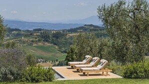 A wooden deck with lounge chairs overlooking a scenic landscape. - Villa Miniato by MMega (San Miniato)