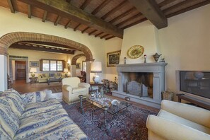 Ein geräumiges Wohnzimmer mit Kamin, Sofas und Fernseher.