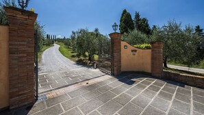 A paved driveway leading to a gated entrance with a lamp post and a brick wall. - Villa Miniato by MMega (San Miniato)