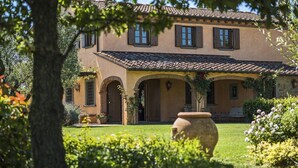 A two-story building with a stone roof, arched doorways, and a garden with a large pot. - Villa Miniato by MMega (San Miniato)