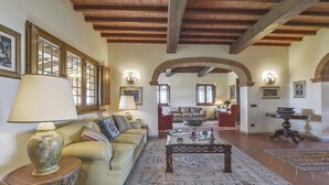 A spacious living room with a sofa, armchairs, a coffee table, and a fireplace. - Villa Miniato by MMega (San Miniato)
