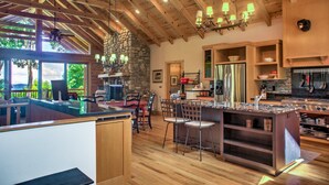 A spacious kitchen with wooden beams, a stone wall, and a large island with bar stools.