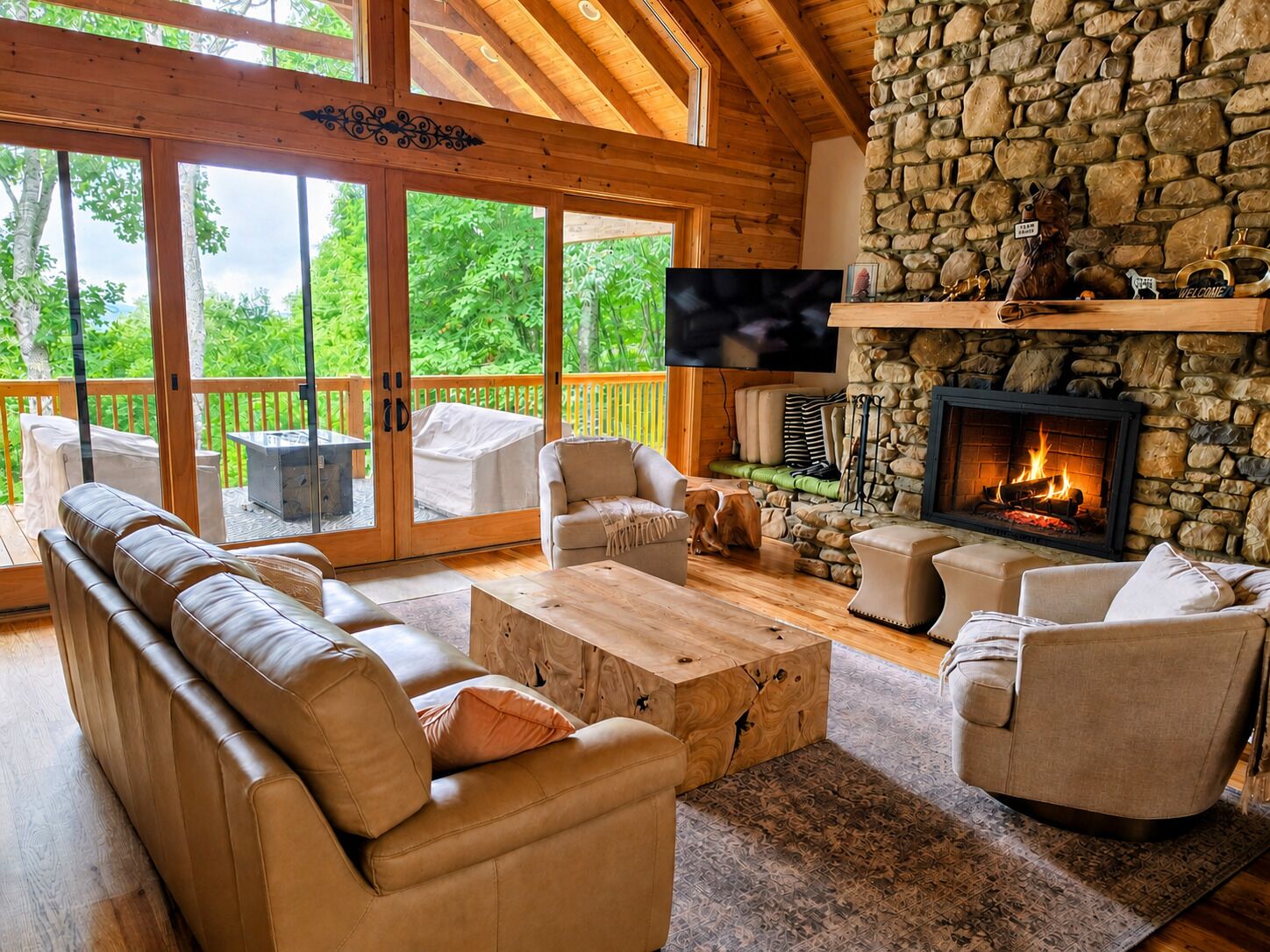 A cozy living room with a stone fireplace, leather sofas, and a large TV.