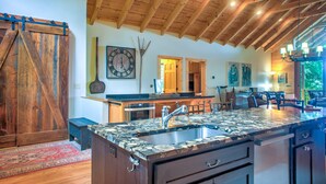 A spacious kitchen with wooden beams, a large island with a sink, and a rustic barn door.