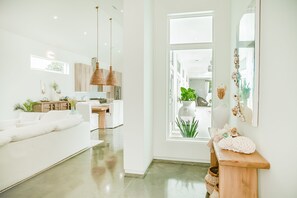 A modern, well-lit living room with a sofa, dining area, and kitchen in the background. - Location, comfort, and 5 beach accesses to more than one mile of deeded beach! (Seagrove Beach)