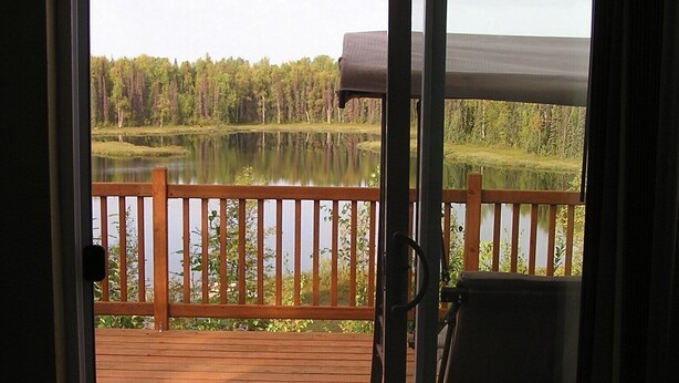 A wooden deck with a view of a lake and forest.