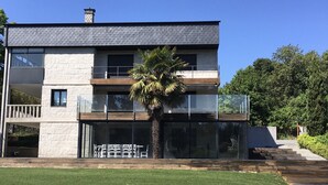 Un edificio moderno de dos pisos con fachada de piedra, ventanas grandes y un balcón.