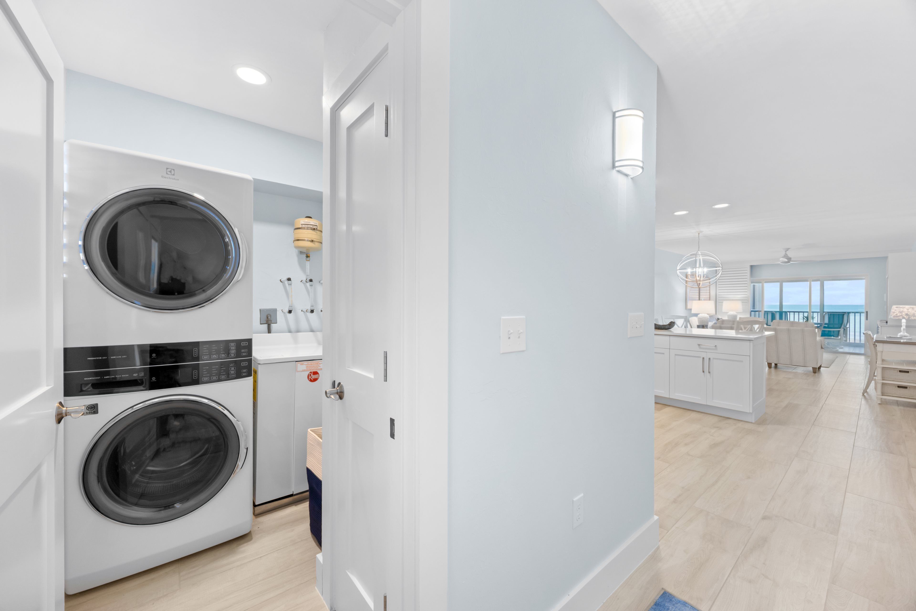 A modern kitchen with white cabinets and a central island, a dining area with a view, and a laundry room with two washing machines.