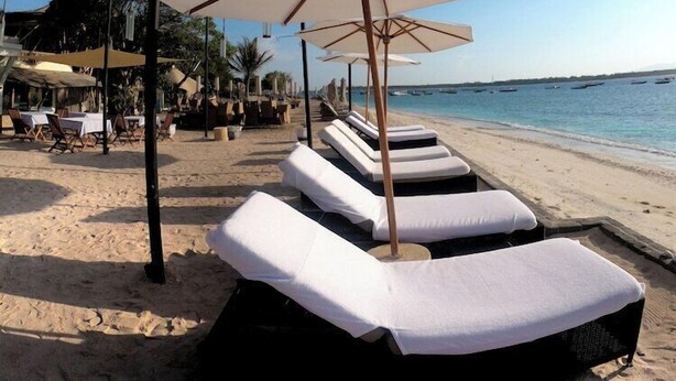 A beach with sun loungers and umbrellas, a dining area, and a view of the sea. - Ko Ko Mo Resort (Gili Trawangan)