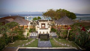A poolside view of a resort with a central building, a pool, and a view of the ocean. - Ko Ko Mo Resort (Gili Trawangan)