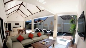 A spacious living area with a sofa, coffee table, and a TV on a wooden stand. - Ko Ko Mo Resort (Gili Trawangan)