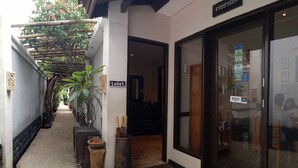 A corridor with a toilet sign, a BUKA shop, and a reception area. - Ko Ko Mo Resort (Gili Trawangan)
