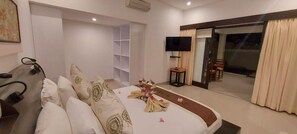 A hotel room with a bed, a TV, a sliding glass door, and a small table. - Ko Ko Mo Resort (Gili Trawangan)