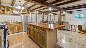 Une cuisine spacieuse dotée de meubles en bois, d’un îlot central et d’un réfrigérateur en acier inoxydable.