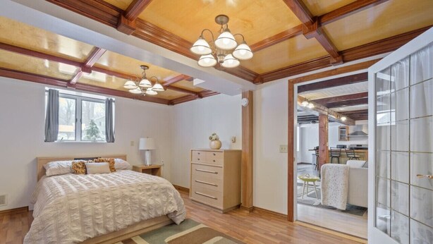 Une chambre à coucher comprenant un lit, une commode et donnant sur le salon.