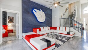 A spacious living room with a sectional sofa, a ceiling fan, and a staircase. - Star Wars Villa - 10 Mins to Disney (Kissimmee)