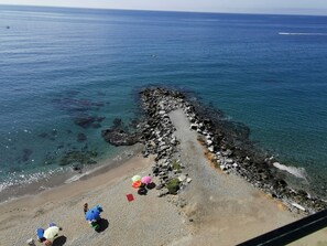 A rocky shoreline with clear water and a few umbrellas on the beach. - La Perla Benalmadena Apartment 1st Line Apartment (BENALMADENA COSTA)