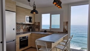 Een moderne keuken met uitzicht op zee, voorzien van een koelkast, magnetron en een groot kookeiland met barkrukken.