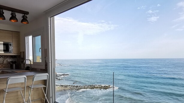 Een moderne keuken met een groot raam met uitzicht op de oceaan.