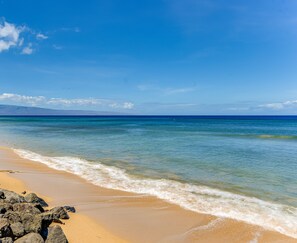 A beach with clear blue water, sandy shore, and rocky outcrops. - Large Remodeled with Ocean View (Lahaina)