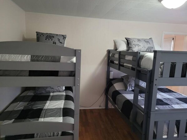 A bunk bed room with two bunk beds, each with a checkered bedspread and pillows with a checkered pattern. - Rustic Hook Lodge, Steelhead Suite (Wellston)