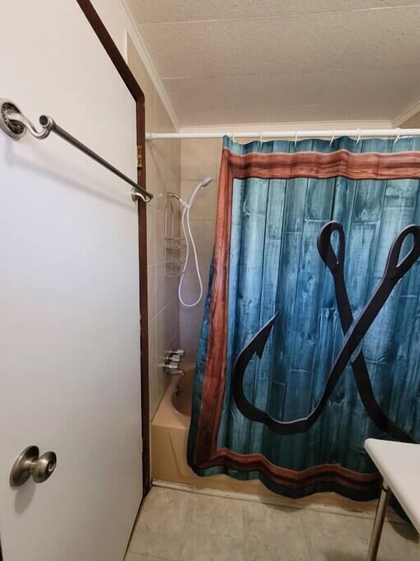 A bathroom with a shower, a towel rack, and a curtain with a large black letter 'C'. - Rustic Hook Lodge, Steelhead Suite (Wellston)