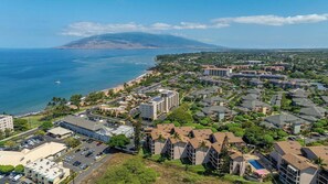 A coastal town with a mix of residential and commercial buildings, a beach, and a mountain in the background.