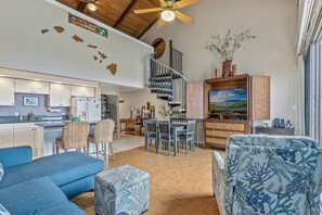 A spacious living area with a kitchen, dining area, and a staircase leading to a loft.
