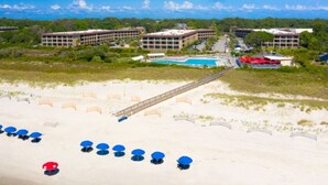 Ett hotell vid stranden med flera byggnader, en swimmingpool och parasoller.