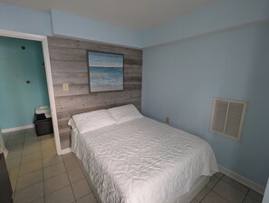 A bedroom with a bed, a painting, a nightstand, and a door. - 2 bedroom condo close to the boardwalk and attractions such as Jolly Roger (Ocean City)