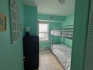 A room with teal walls, a bunk bed, a desk with a lamp, and a window with blinds. - 2 bedroom condo close to the boardwalk and attractions such as Jolly Roger (Ocean City)