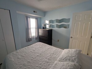 Une chambre à coucher avec un lit, une commode, un miroir et une porte.
