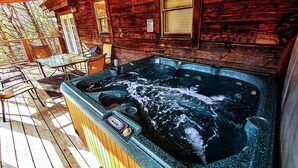 Une cabane en bois avec un jacuzzi sur la terrasse.