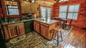 L’intérieur d’une cabane en bois comprend une cuisine, un coin repas et une grande fenêtre.