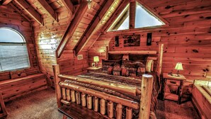 Une chambre dans un chalet en rondins, avec un lit en bois, un banc, une fenêtre et une lampe sur une table de chevet.