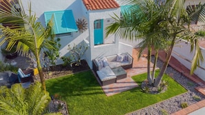 Una casa moderna con un pequeño patio, una puerta azul y fachada blanca.