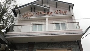 Un hotel llamado 'Phương Dương' con una estructura de dos pisos, ventanas amplias y un letrero que indica 'CÔN PHÒNG'.