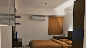 Ein modernes Hotelzimmer mit Bett, Nachttisch und kleinem Schreibtisch mit Stuhl.