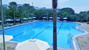 Ein Schwimmbecken mit mehreren Bahnen, umgeben von Liegestühlen und Sonnenschirmen.