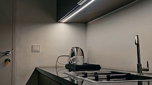 Eine moderne Küche mit einer Edelstahlarbeitsplatte, einer Kaffeemaschine und einem Wasserhahn.