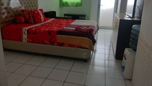 A hotel room with a bed, a desk, a water dispenser, and a television. - Dinda Apartment Gunung Putri Square (Gunung Putri)