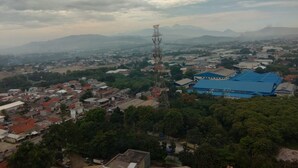 A panoramic view of a town with a prominent communication tower, a blue-roofed building, and surrounding greenery. - Dinda Apartment Gunung Putri Square (Gunung Putri)
