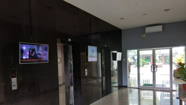 A modern lobby with a glass door entrance, a digital screen displaying news, and a clean, tiled floor. - Dinda Apartment Gunung Putri Square (Gunung Putri)