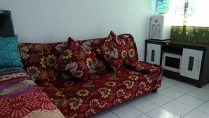 A sofa with floral upholstery, a water dispenser, and a cabinet with a mirror. - Dinda Apartment Gunung Putri Square (Gunung Putri)