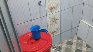 Un baño pequeño con inodoro, un bote de basura rojo y baldosas de suelo estampadas.