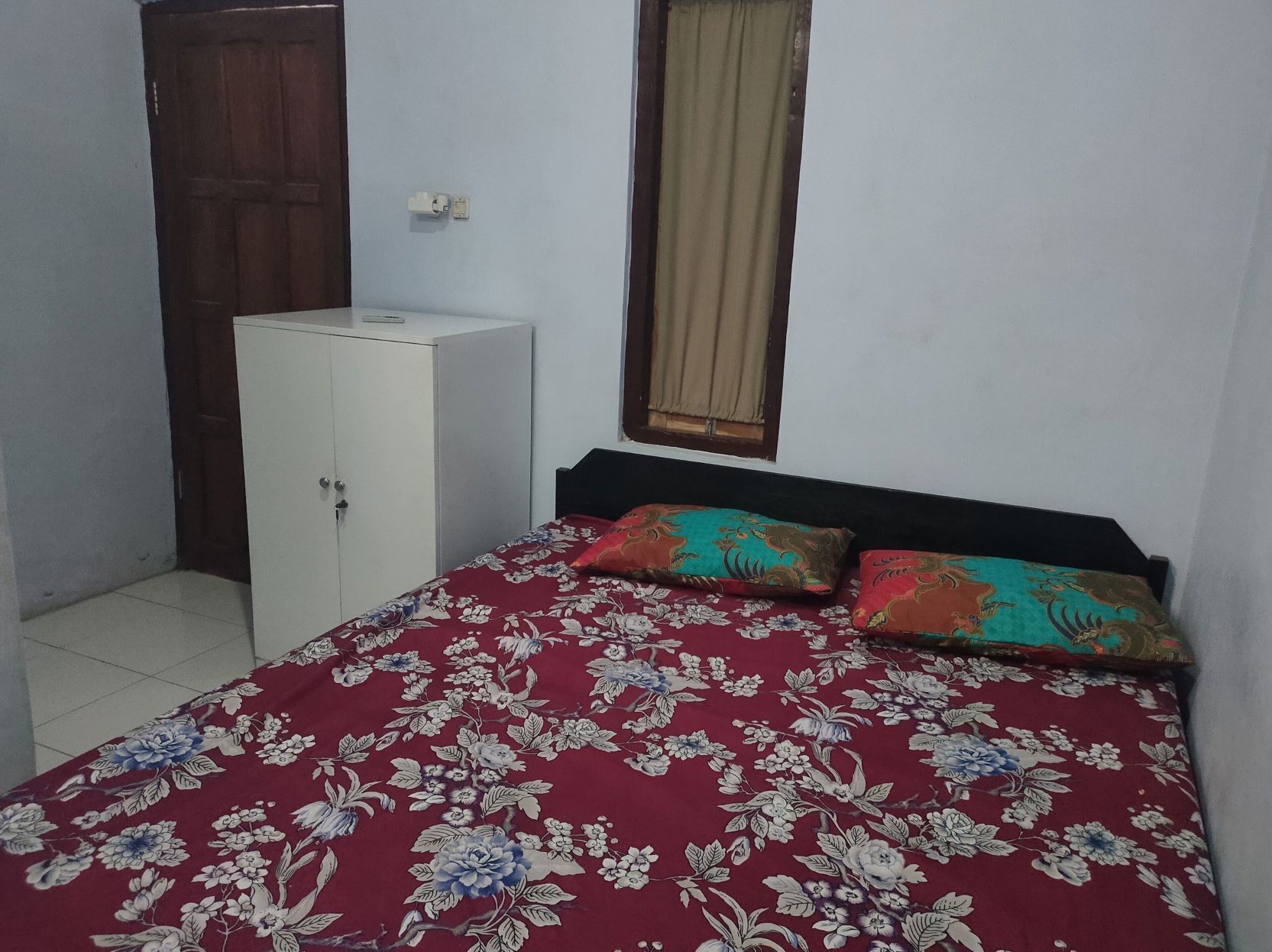 A bedroom with a bed, a wardrobe, and a window with curtains.