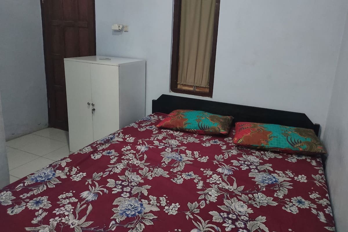 A bedroom with a bed, a wardrobe, and a window with curtains.